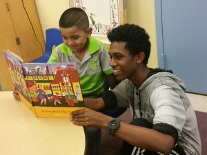 Teen and child read picture book together