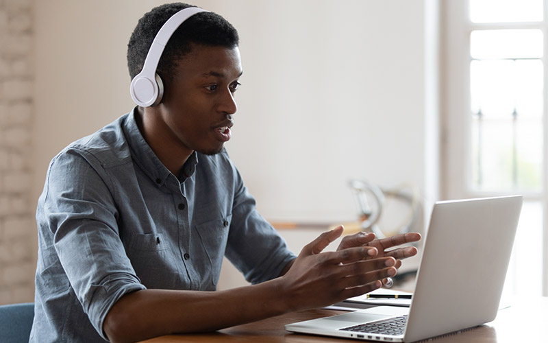 Black student wearing wireless headphones during a virtual tutoring session